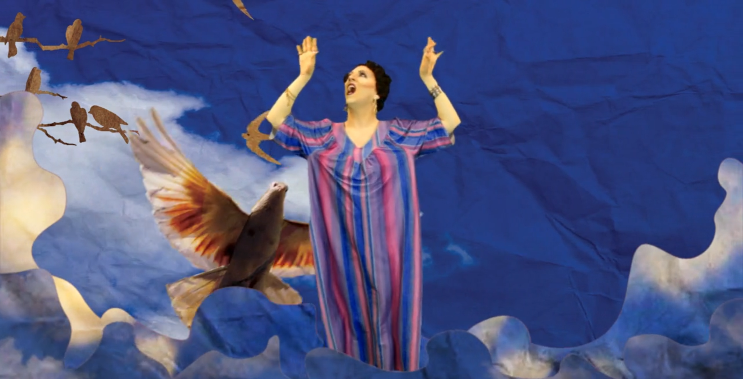 Drag queen in striped caftan with arms raised, surrounded by paper cut-out birds and clouds against a blue sky.